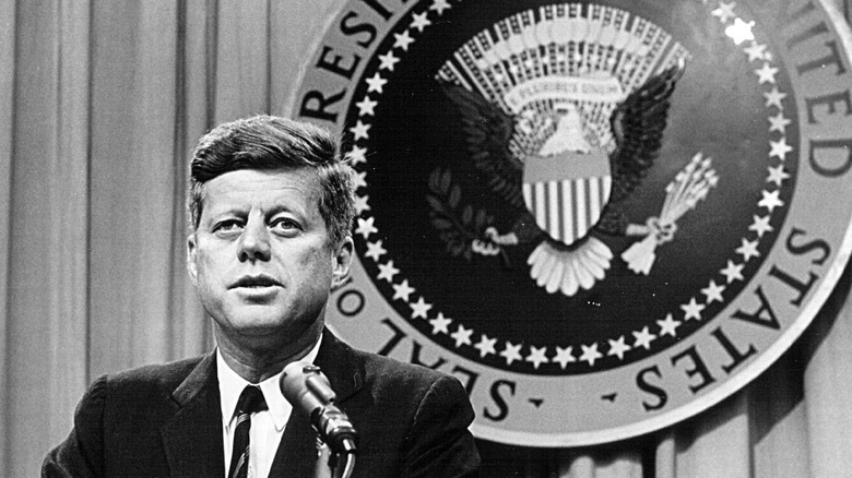 John F. Kennedy in front of presidential seal