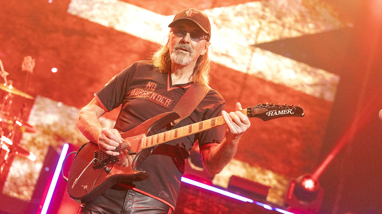 Glenn Tipton playing guitar orange background