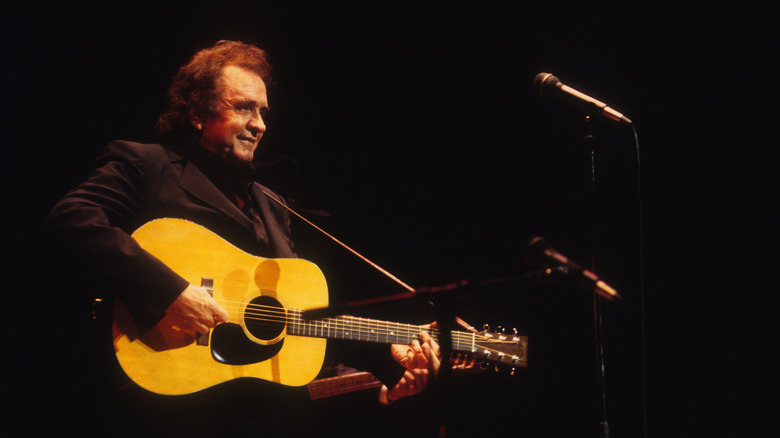 Johnny Cash performing with acoustic guitar in front of microphone