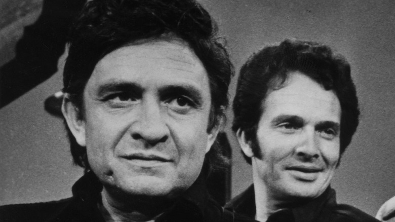 Merle Haggard standing behind Johnny Cash