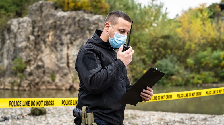 Homicide detective at crime scene walkie talkie