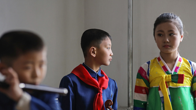 Three North Korean children in uniforms