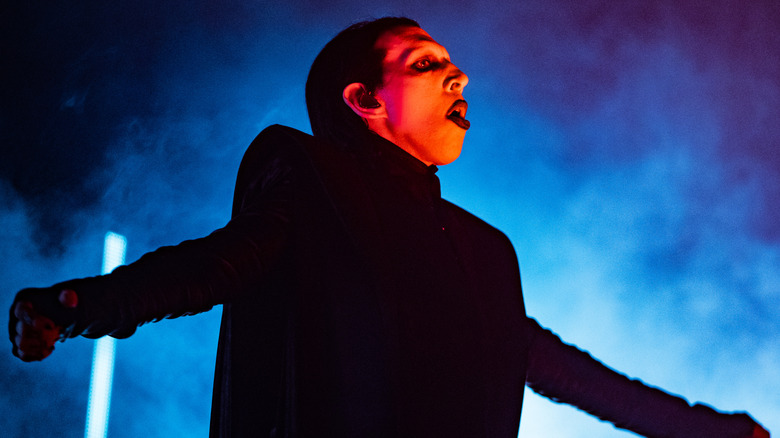 Marilyn Manson performing on blue-lit stage in black costume