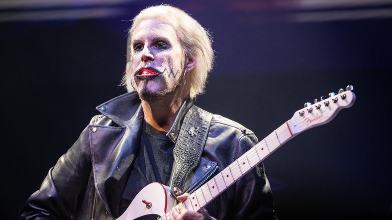 John 5 playing guitar on stage with face paint and leather jacket