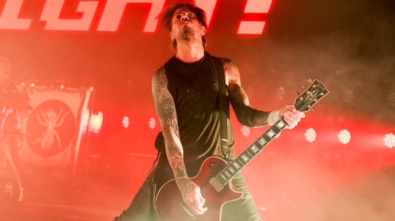 Rob Holliday playing guitar on red-lit stage