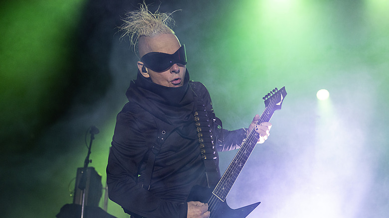 Tim Skold playing guitar on stage in wraparound sunglasses