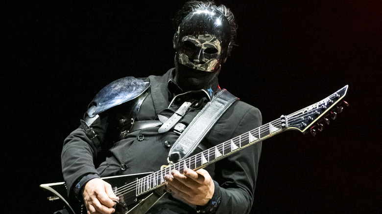 Wes Borland playing guitar on stage in shiny mask