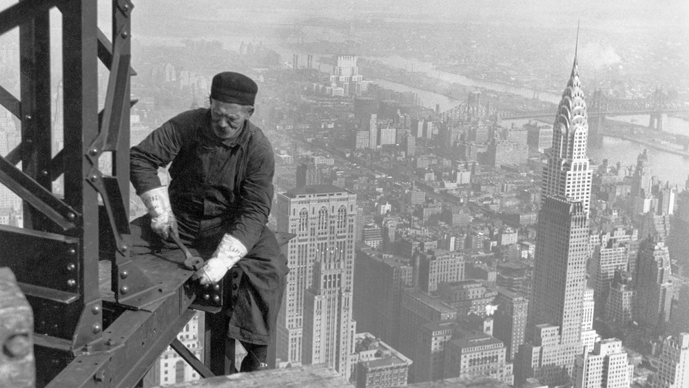 Workman on skyscraper with New York City behind him