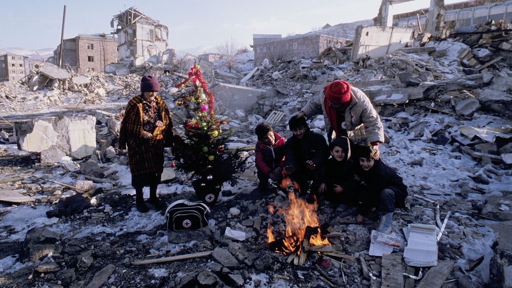 Pictured: family in ruins with Christmas tree at open fire. 