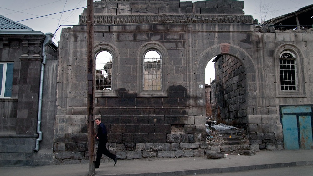 Gyumri resident walks by a building destroyed by the 1988 Earthquake on March 21, 2005 
