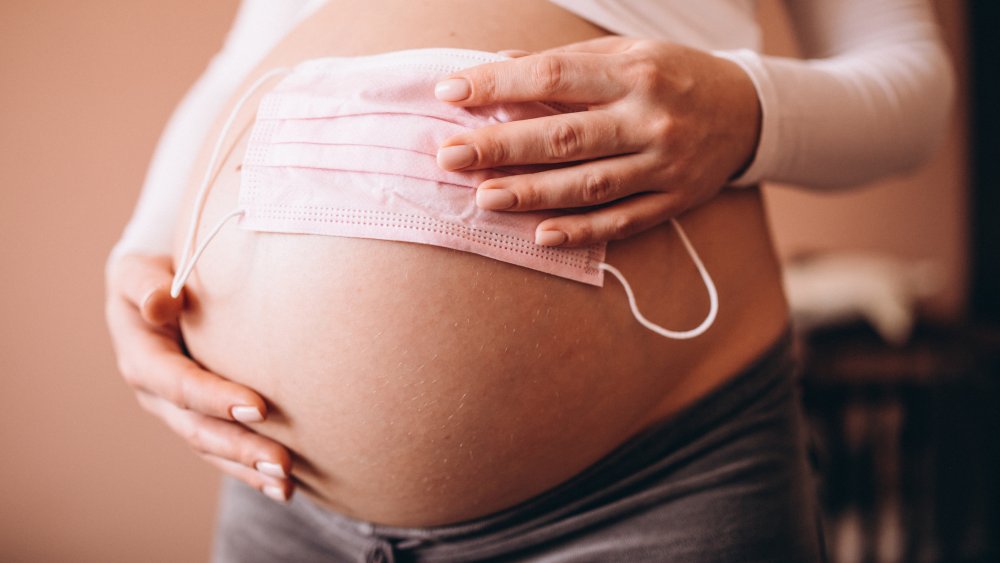 A pregnant woman holding a medical mask