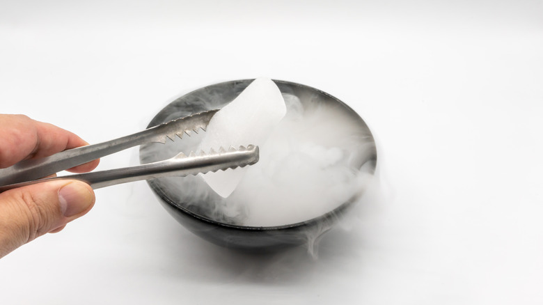 Using tongs to hold dry ice