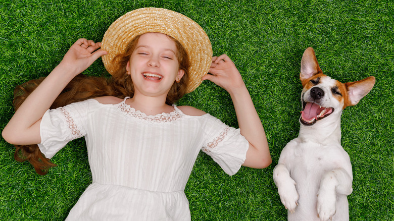 girl and dog smiling in grass
