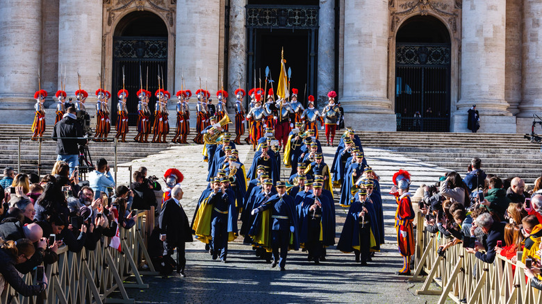 Marching band leading Swiss Guard down steps of the Basilica