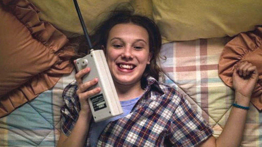 Eleven talking into a Walkie Talkie.