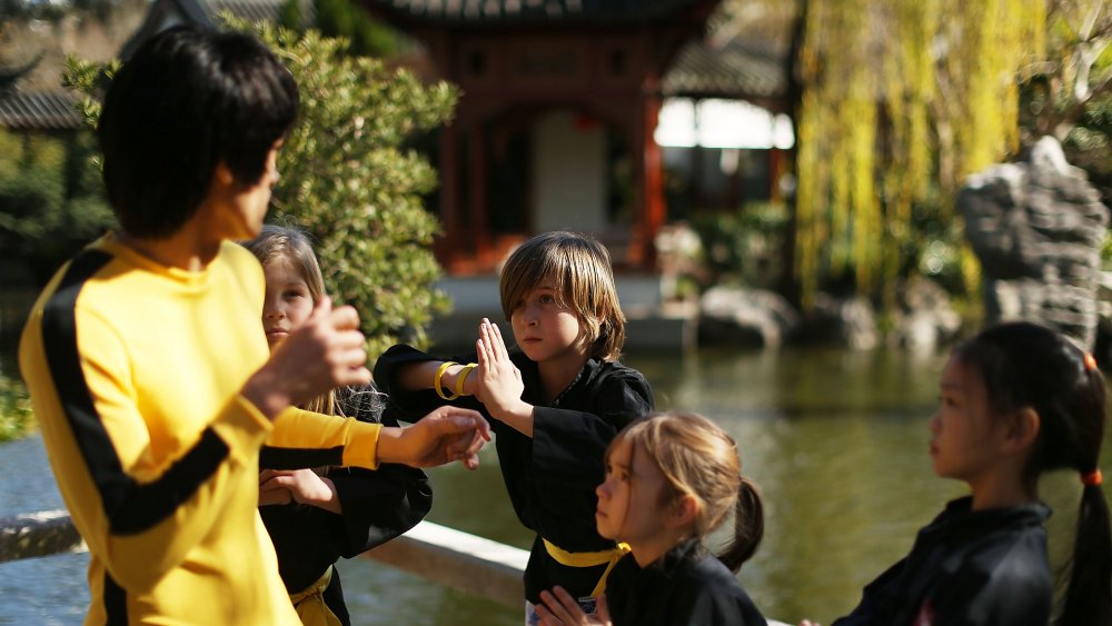 Bruce Lee's statue with students of martial arts 