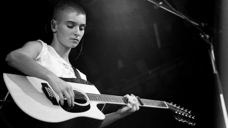 Sinead O'Connor black and white playing guitar on stage