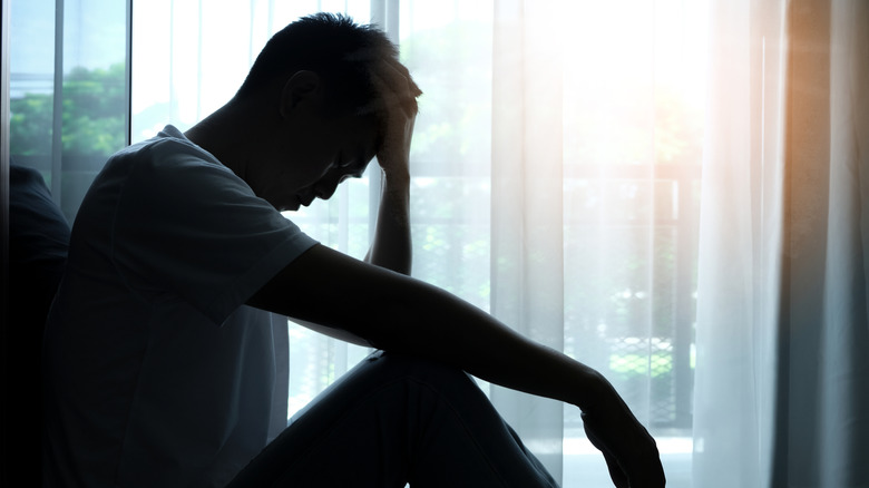 Man sat by window looking downcast