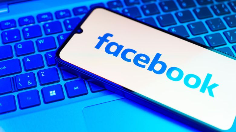 facebook logo displayed on phone resting on keyboard