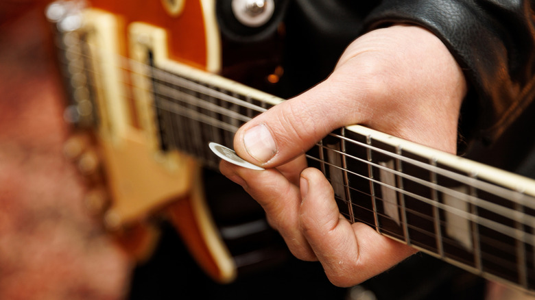 Guitarist holding pick and guitar neck