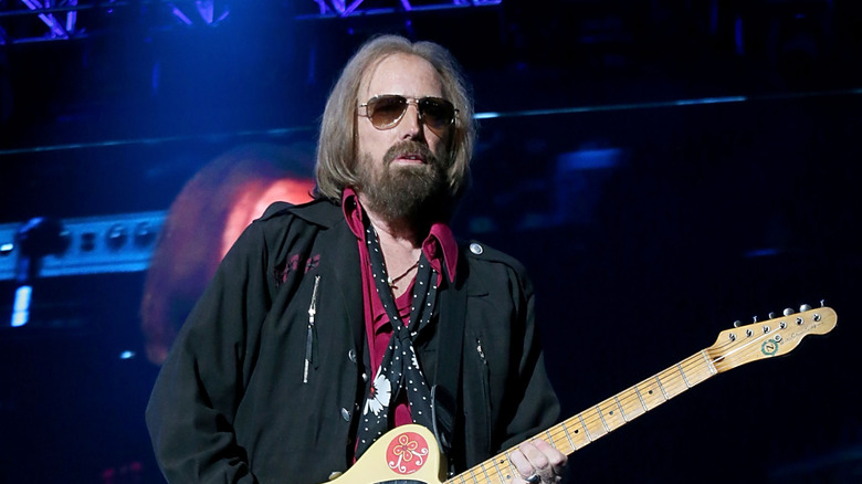 tom petty on stage in red shirt and sunglasses