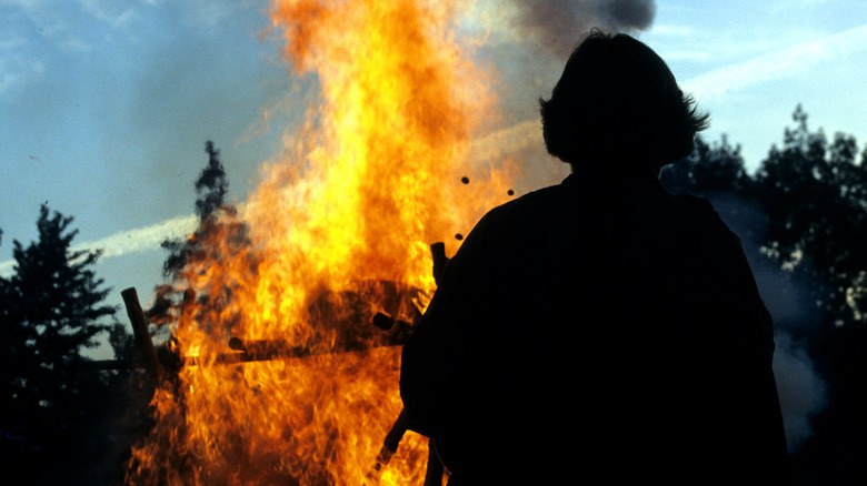 Person silhouetted against large funeral pyre