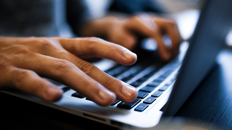Black hands type on keyboard