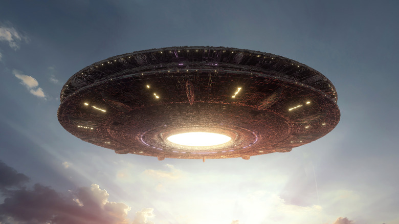 Alien flying saucer hovering above a field