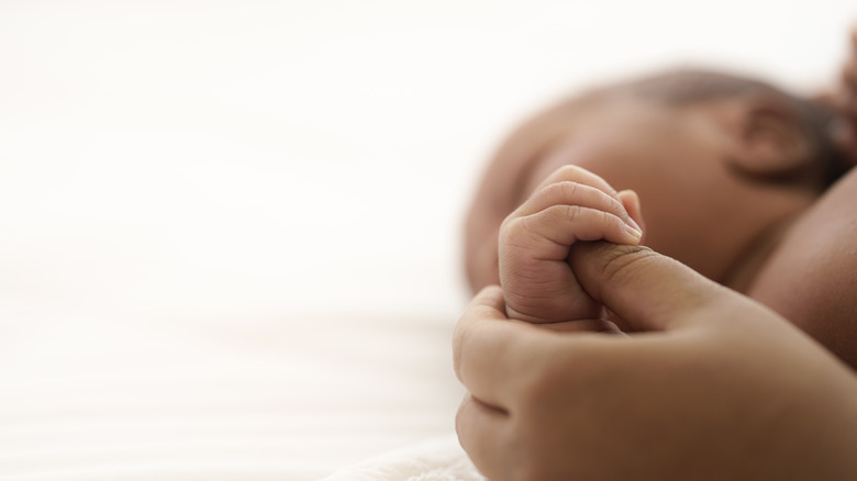 baby holding mother's thumb