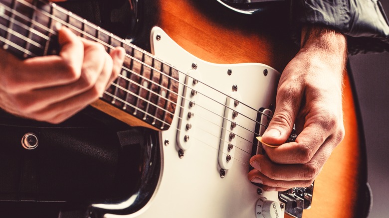 Hands strum a guitar