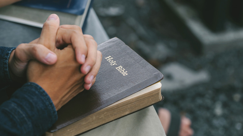 folded hands over a bible