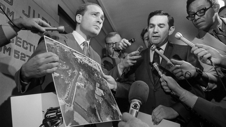 man holds photo of LaBianca home surrounded by press with microphones