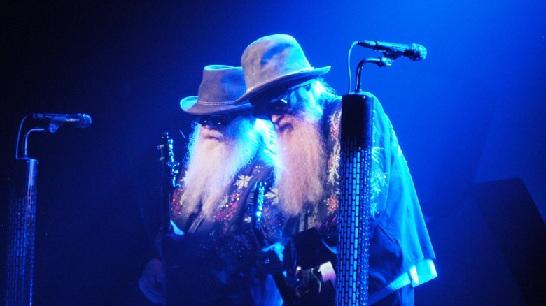 ZZ Top's Billy Gibbons and Dusty Hill stand in a blue light on stage.