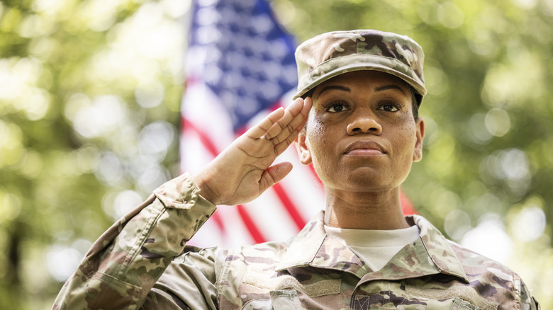 Female solider giving salute in front of American flag