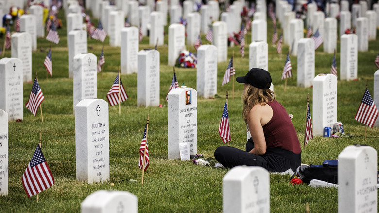 Woman sitting at headstone in Arlington Cemetery on Memorial Day