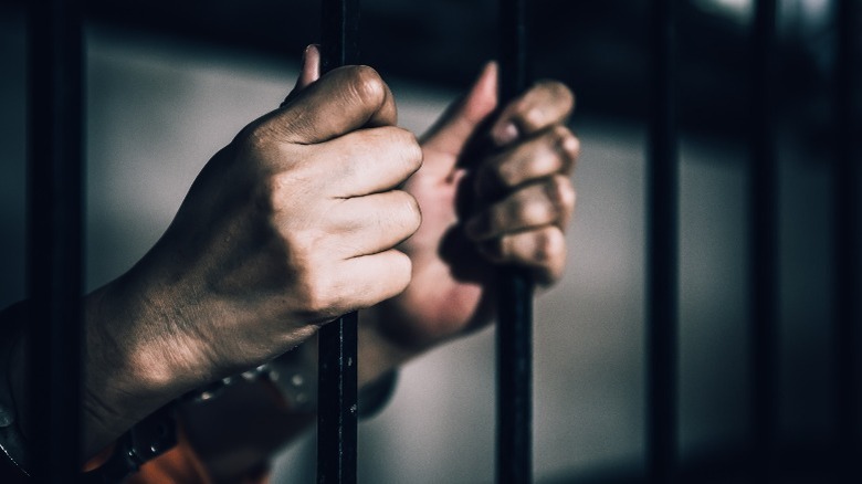 man with hands on prison bars