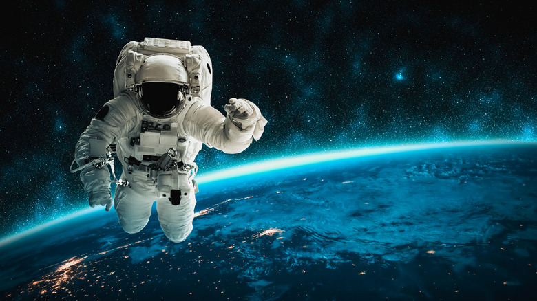 Astronaut in space above distant Earth