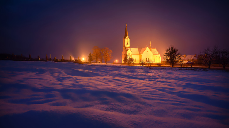 Nighttime church aglow in snow 