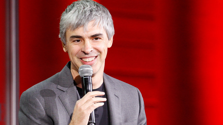 larry page smiling with mic in grey suit