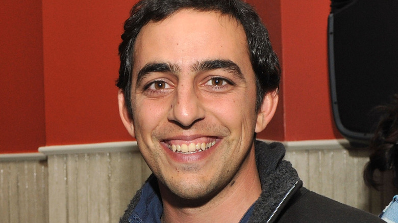 salar kamangar smiling in black jacket by red wall