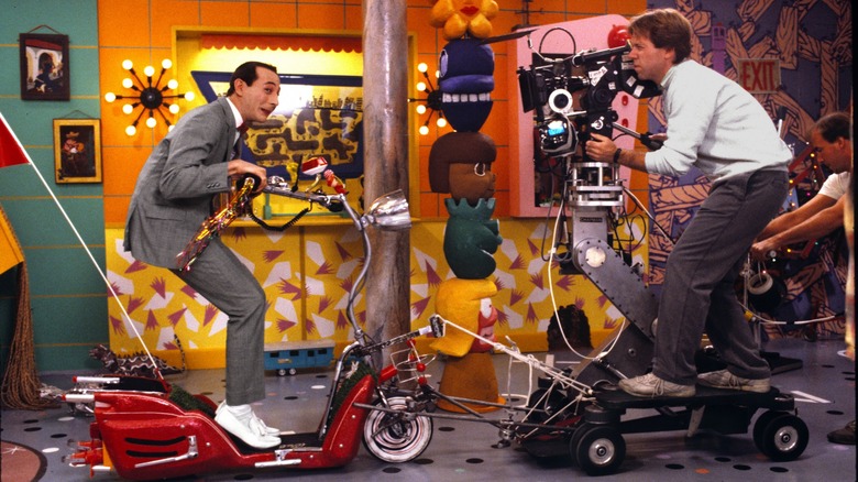 Pee-wee Herman riding scooter on set