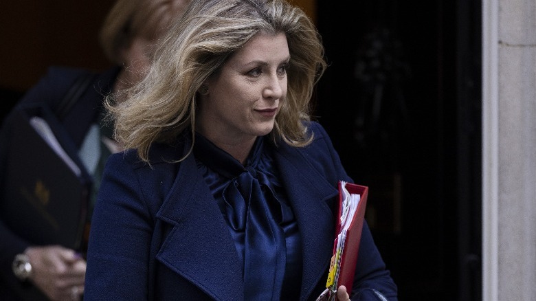 Penny Mordaunt smiling, carrying notebook