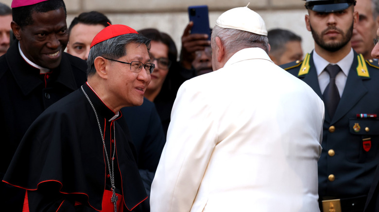 Cardinal Tagle shaking hands with Pope Francis outdoors