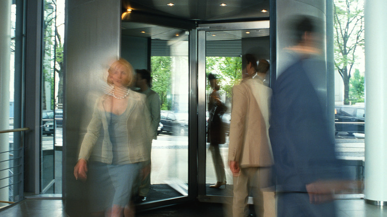 Blurred people using a revolving door