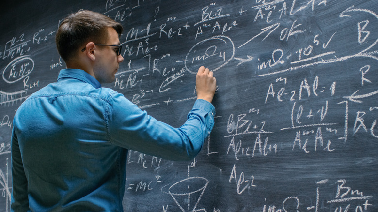 A man working on math equations on a chalkboard