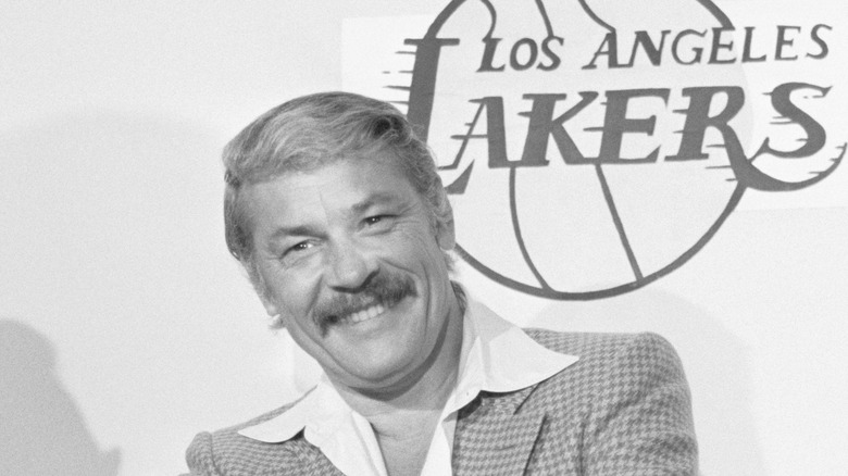 Jerry Buss smiling by LA Lakers logo