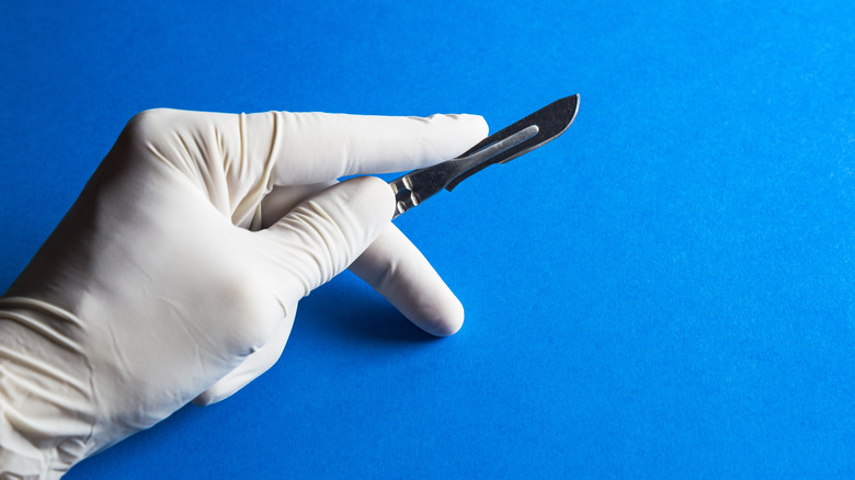 gloved hand holding scalpel