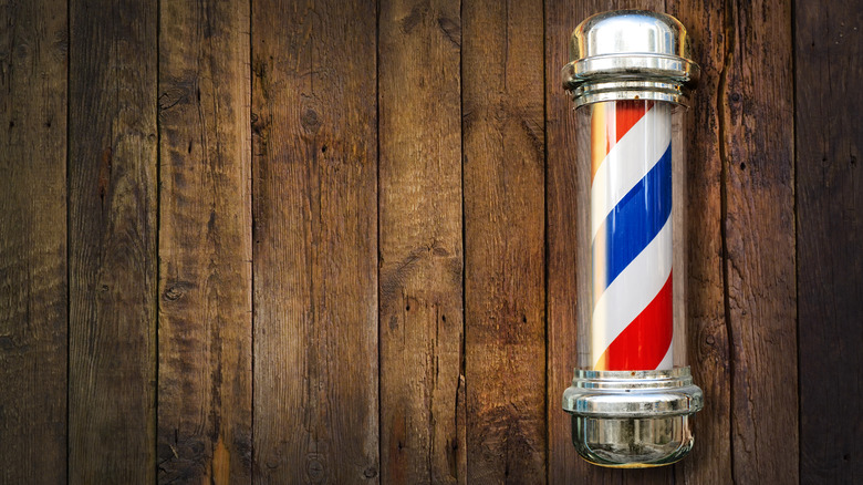 Barber pole on right side against wooden background