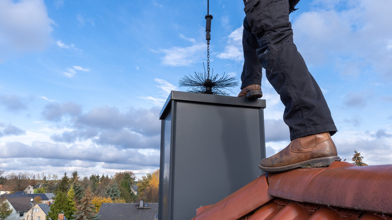 A man on a roof chimney sweeping