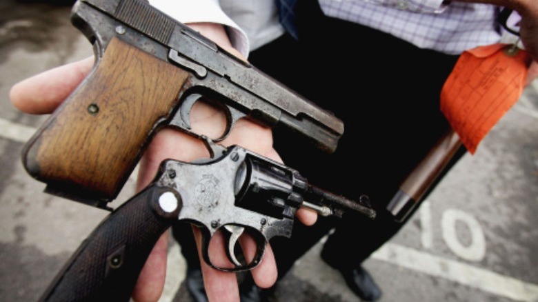 man holding gun and revolver